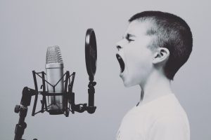 A boy shouts loudly into a microphone