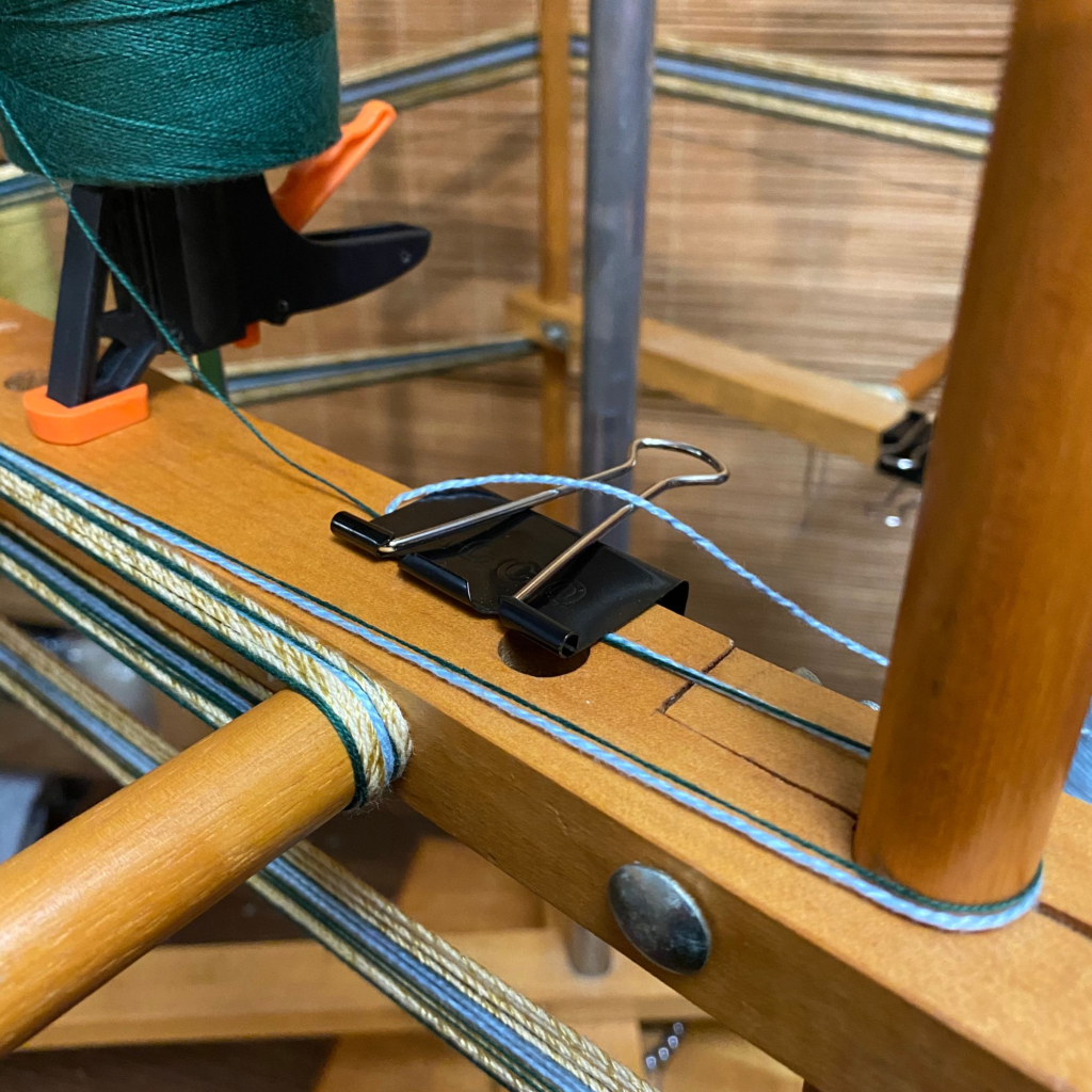 Another view of the binder clip on the warping mill that includes a cone of yarn "on hold" on the clamp.