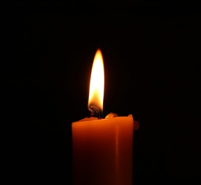 a single red candle with a yellow flame with a black background